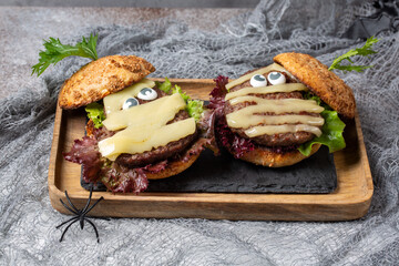 Homemade mummy shaped burger for Halloween celebration on gray background. Halloween food and decoration.