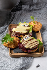 Homemade mummy shaped burger for Halloween celebration on gray background. Halloween food and decoration.