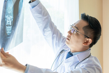 Asian doctor looking at x-ray film of patient