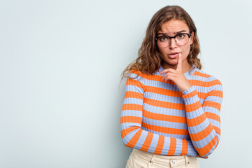 Young caucasian woman isolated on blue background looking sideways with doubtful and skeptical expression.