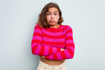 Obraz premium Young caucasian woman isolated on blue background blows cheeks, has tired expression. Facial expression concept.