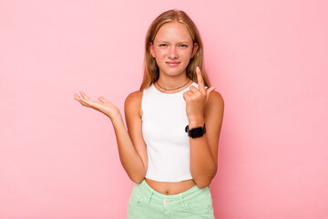 Caucasian teen girl isolated on pink background holding and showing a product on hand.