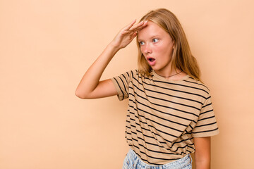 Caucasian teen girl isolated on beige background looking far away keeping hand on forehead.