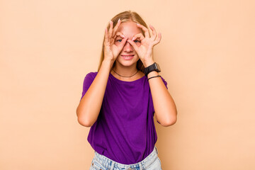 Caucasian teen girl isolated on beige background excited keeping ok gesture on eye.