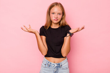 Caucasian teen girl isolated on pink background doubting and shrugging shoulders in questioning...