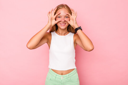 Caucasian teen girl isolated on pink background keeping eyes opened to find a success opportunity.