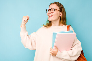 Young student caucasian woman isolated on blue background raising fist after a victory, winner concept.