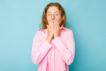 Young caucasian woman isolated on blue background shocked covering mouth with hands.