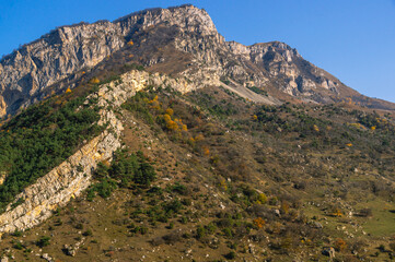 Autumn landscape in the mountains. Yellowed trees in autumn in the mountains of North Ossetia. Mountain gorges. View of the mountain peaks. Nature in the mountains.