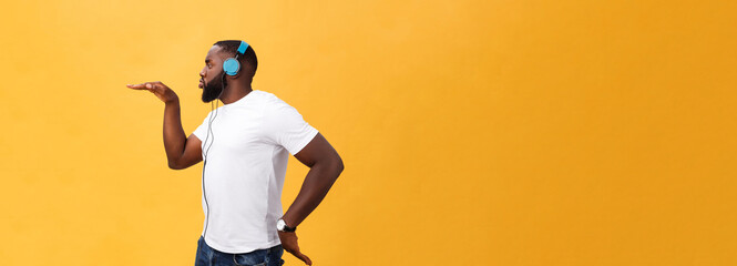 Young African American man wearing headphone and enjoy music dancing over yellow gold Background