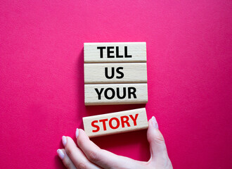 Tell us your story symbol. Concept words Tell us your story on wooden blocks. Beautiful red background. Businessman hand. Business and Tell us your story concept. Copy space.