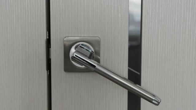 Pressing a metal modern handle and opening the door, close-up