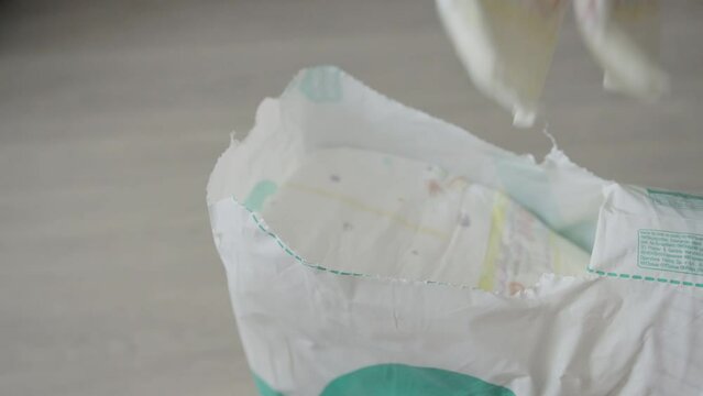 A man takes several diapers from the package to replace his child. Close-up