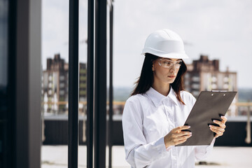 Business woman in white helmet standing on the roof building