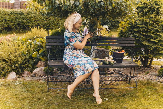 A woman is sitting on a bench and resting after a hard day in the garden on hot crazy summer days