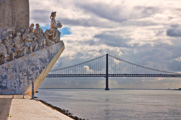 Monument to the Discoveries (Padrao dos Descobrimentos) at the Tagus river with view on 25th of April Bridge (Lisbon - Portugal) - obrazy, fototapety, plakaty