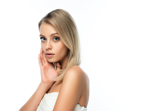 blonde model with bare shoulders and blue eyes looking at camera isolated on white.