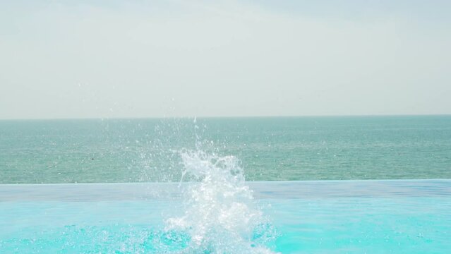 Happy Kid Jumping Bombshell into Outdoor Infinity Pool Water. Little Girl Having Fun in Swimming Infinity Pool on Sunny Summer Day. Happy Family Holiday.