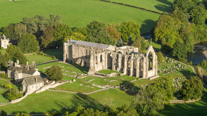 Early morning sunshine illuminates Bolton Abbey in Wharfedale, North Yorkshire, England, takes its name from the ruins of the 12th-century Augustinian monastery now known as Bolton Priory - obrazy, fototapety, plakaty