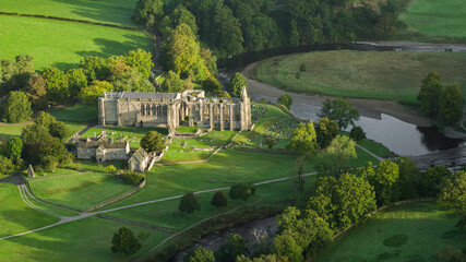 Fototapeta na wymiar Early morning sunshine illuminates Bolton Abbey in Wharfedale, North Yorkshire, England, takes its name from the ruins of the 12th-century Augustinian monastery now known as Bolton Priory