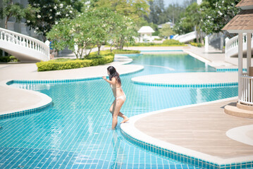 Smiling Beautiful Woman In Bikini With Perfect Slim Body Posing at swiming pool on a hot summer day.