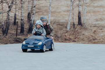 Two happy kids having fun drive a blue toy car, road trip adventure concept