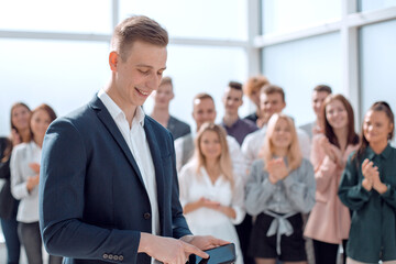 business guy with smartphone standing in front of a group of young people.