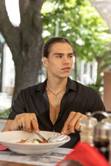 Young man eating alone in the outdoor restaurant