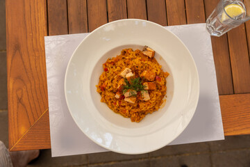 Risotto served in white plate on a restaurant table, top view