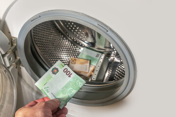 Money laundering concept, a man hand adding the 100 euro banknote into a pile of euro banknotes to...