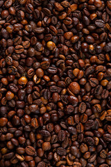 High roast coffee beans covered with water drops, structured and textured background