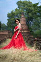 Fototapeta premium Beautiful portrait pretty woman red dressed as an Indian sexy girl with red lips. Young Hindu Pakistani Bride and glamour makeup in a fashion jewelry set.