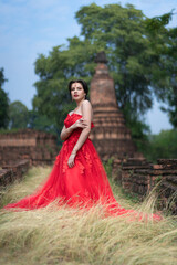 Fototapeta premium Beautiful portrait pretty woman red dressed as an Indian sexy girl with red lips. Young Hindu Pakistani Bride and glamour makeup in a fashion jewelry set.