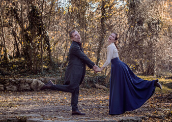 Vampire man wearing victorian suit with vampire woman in the autumn forest. Vintage medieval concept style.