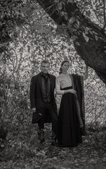 Vampire man wearing victorian suit with vampire woman in the autumn forest. Vintage medieval...