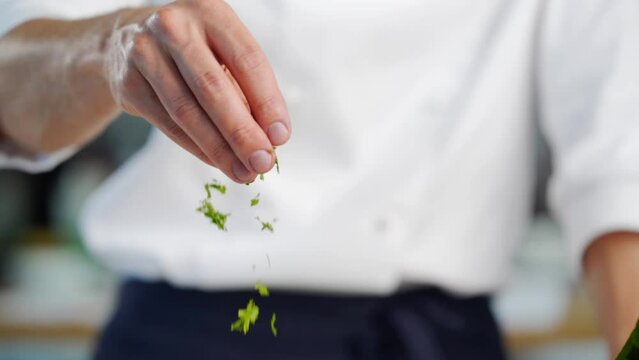 chef adding parsley to omelette with tomato in white plate in loft style kitchen