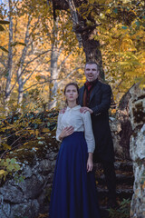 Vampire man wearing victorian suit with vampire woman in the autumn forest. Vintage medieval concept style.