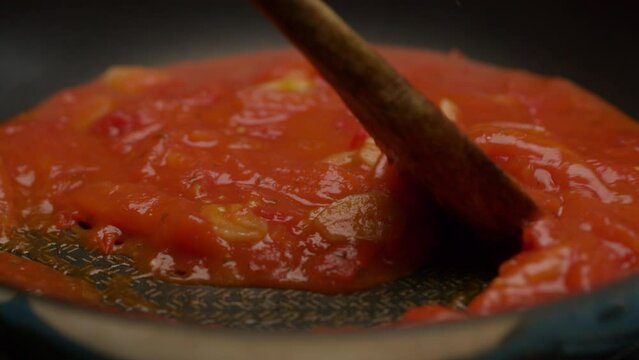 Cooking tomato sauce with garlic on frying pan in slow motion.