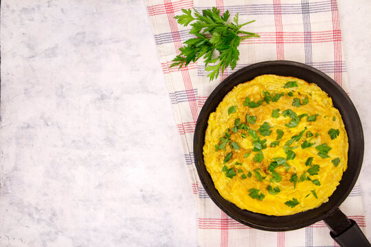 omelette with parsley in a pan on a gray background top view - Powered by Adobe
