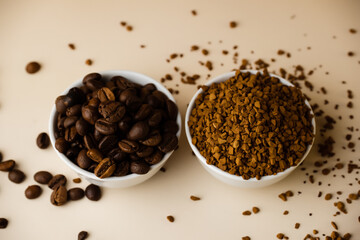 Two small bowls filled with coffee beans and instant coffee on a light table, beige background.