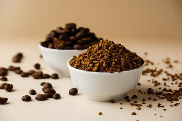 Two small bowls filled with coffee beans and instant coffee on a light table, beige background.