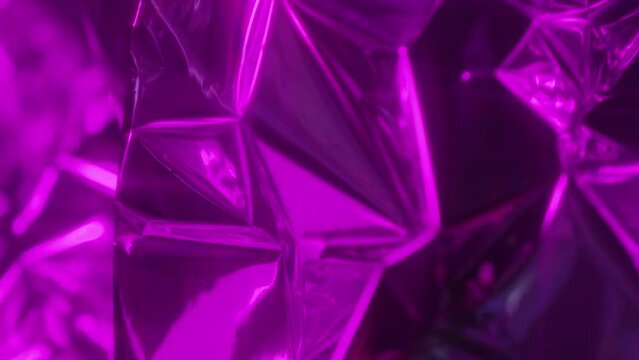 Tracking close up shot of metallic prism texture of magenta color with light reflection