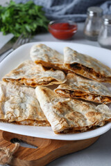 Mexican snack quesadilla from tortilla with chicken, cheese and champignon in white plate on wooden board, Vertical format