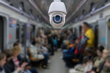 Fototapeta premium Security camera monitoring attach on ceiling inside subway metro train to surveillance safety of passenger in rush hour and can watch all time, blur people background.