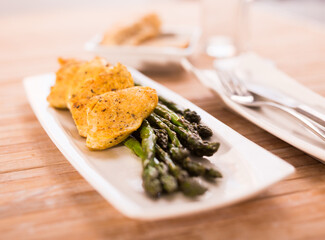 fried chicken breast pieces with asparagus on white plate