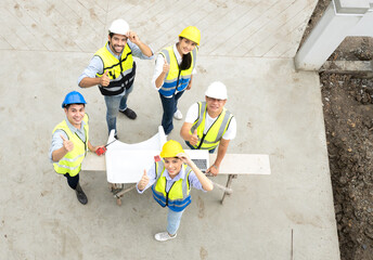 Engineer man and architect teamwork wear safety helmet meeting at construction site with blueprint for engineering project design, top view. High angle view of construction workers brainstorming.