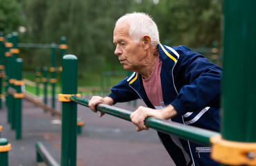 Old man in sportswear exercising push-ups outdoors