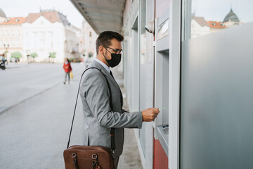 Handsome middle age businessman with protective face mask and eyeglasses standing on city street...
