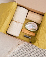 Gift box with natural household items - luffa, muslin towel, shell and a small block of Palo Santo wood for aromatherapy and relaxation. View from above.