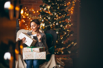 Woman sitting in chair by Christmas tree